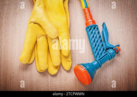 Leather work gloves garden rubber hose nozzle on wooden board gardening concept Stock Photo