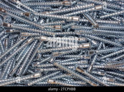 A close-up image of a metal sheet with multiple screws and nuts scattered across the surface Stock Photo