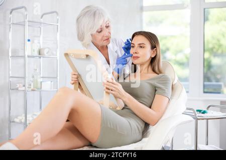 Young patient looking in mirror at clinic. Stock Photo
