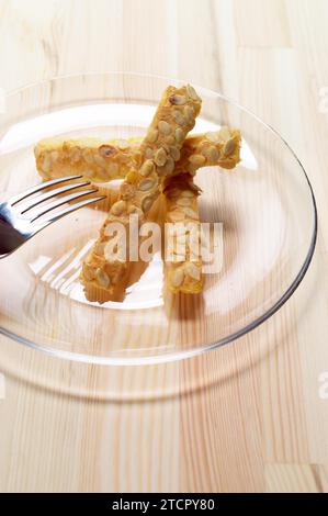 Sunflower seeds puff pastry sticks on a glass transparent plate over pine wood table Stock Photo