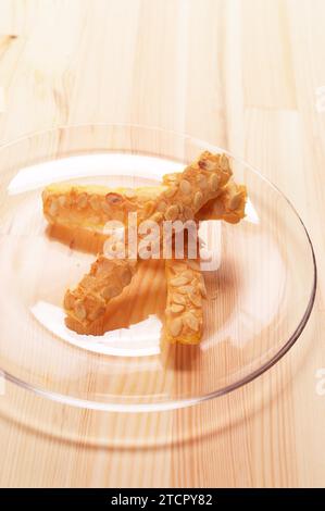 Sunflower seeds puff pastry sticks on a glass transparent plate over pine wood table Stock Photo