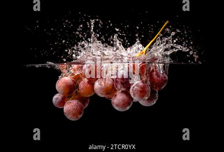 Isolated Red grapes splashing and sinking in water on white background with air bubbles Stock Photo