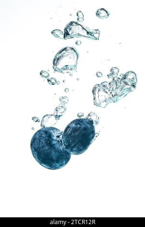 Two blueberry?s splashing into crystal clear water with air bubbles Stock Photo
