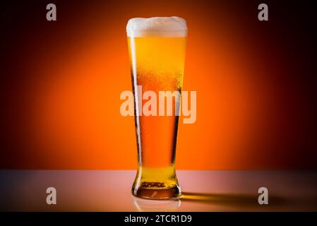Beer glass with drops on a orange background. Alcohol concept. Copy space Stock Photo