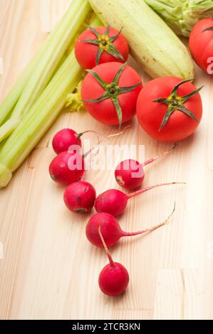 Fresh raddish and vegetables over pine wood table closeup Stock Photo