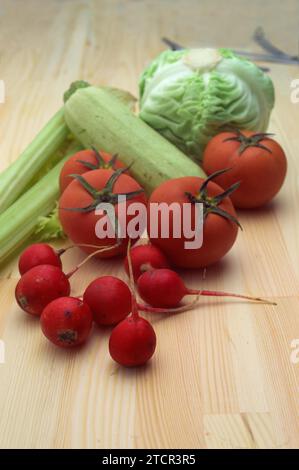 Fresh raddish and vegetables over pine wood table closeup Stock Photo