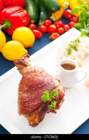 Original German BBQ pork knuckle served with mashed potatoes and sauerkraut, fresh vegetables on background, MORE DELICIOUS FOOD ON PORTFOLIO Stock Photo