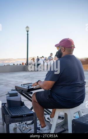 A Serene Sunset Serenade: A Solo Male Musician Rooftop playing music with a Keyboard Stock Photo