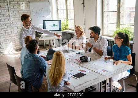 Group of young confident happy business people analyzing data during meeting in the office Stock Photo