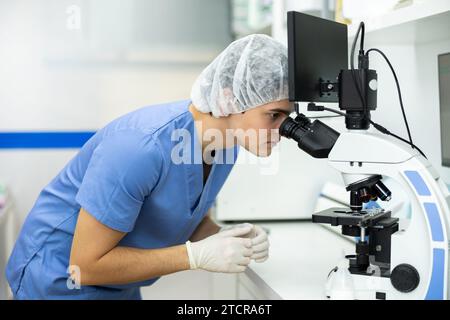 Young veterinarian examining samples under microscope in veterinary office Stock Photo