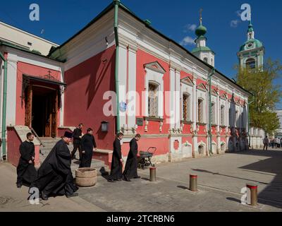 Men dressed in Orthodox black robes walk out of the Church of The Beheading of John The Baptist By Bohr after religious service. Moscow, Russia. Stock Photo