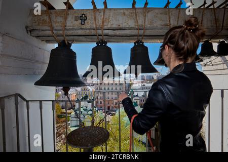 Young woman rings the bells on belfry of the Church of The Beheading of John The Baptist By Bohr during traditional Easter celebration. Moscow, Russia Stock Photo