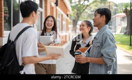 Group of cheerful diverse Asian college students are standing in a campus park and enjoying talking after classes together. Back to school, university Stock Photo
