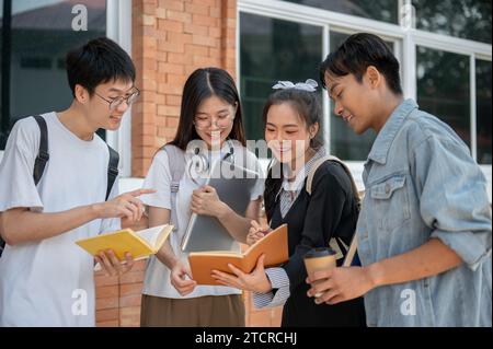 Group of positive diverse young Asian college students are discussing about their project, tutoring each other before the exam, standing outside of th Stock Photo