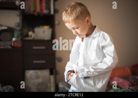 Little the boy dresses a white shirt on the first day of school Stock Photo