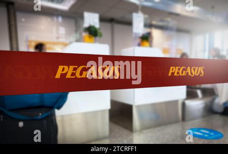 Istanbul, TR, 30 Nov. 30 2023: Vibrant red queue divider with Pegasus Airlines branding in bold yellow letters, prominently displayed in a blurred air Stock Photo