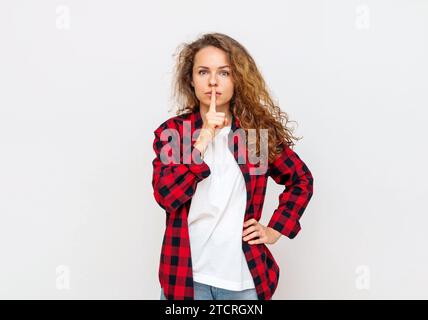 Curly hair woman shushing in front of white background. Stock Photo