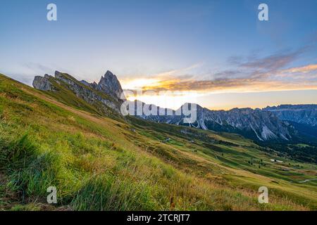 Golden sunrise at Seceda, Dolomites, Italy, A breathtaking spectacle unfolds, casting warm hues on the rugged landscape and meadows, creating a serene Stock Photo