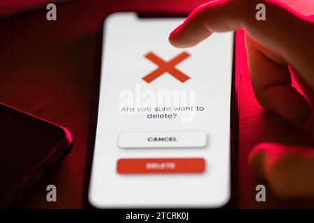 Clicking on red delete button on smartphone app Stock Photo