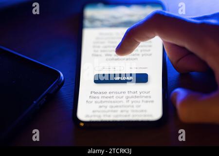 Clicking on upload button on smartphone app Stock Photo