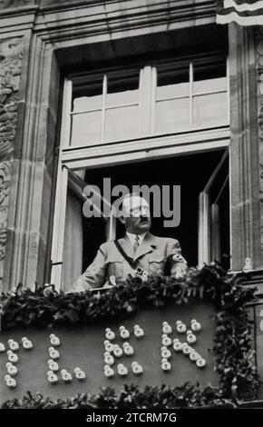 Adolf Hitler is seen peering from a window of the Hotel Deutscher Hof in Nuremberg, the city famously known as the 'City of the Party Rallies.' This image captures a contemplative moment of Hitler overlooking the city that played a pivotal role in Nazi propaganda. The Hotel Deutscher Hof, often used by Nazi officials during the Nuremberg Rallies, provided a strategic viewpoint for Hitler to observe the city that hosted these significant political events, reinforcing his presence and the symbolic importance of Nuremberg in the Nazi narrative. Stock Photo