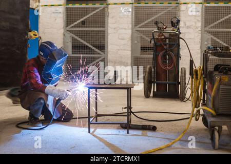 Blue color worker welds the pipe in the workshop in copper mine. Stock Photo