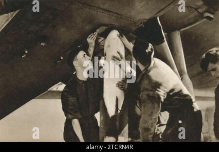 Practice bombs being attached to a German aircraft, part of a training exercise in the Luftwaffe. These exercises, involving non-lethal bombs, were crucial for pilots to learn accurate bomb deployment techniques. Such drills were a key component of the Luftwaffe's preparation for aerial warfare. Dated circa 1935. Stock Photo