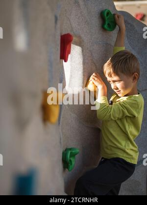 Seven year old boy climbing at artificial wall Stock Photo