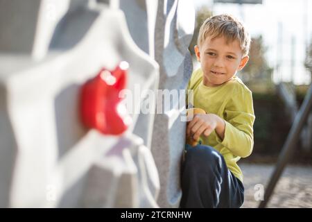 Seven year old boy climbing at artificial wall Stock Photo