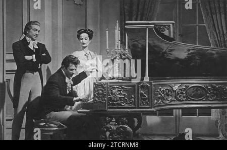 Stephen Bekassy, Cornel Wilde, and Merle Oberon are captured in a moment from 'A Song to Remember' (1945). The film chronicles the life of famed composer Frédéric Chopin, played by Wilde, with Oberon portraying the novelist George Sand, Chopin's lover. Bekassy adds depth to the narrative in his supporting role. Stock Photo