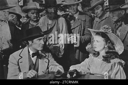 Robert Paige and Deanna Durbin star in 'Can't Help Singing' (1944). The film is set during the California Gold Rush, where Durbin portrays a senator's daughter on a quest to find her runaway fiancé. Paige plays a gambler who becomes an integral part of her journey. Stock Photo