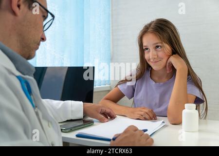 school psychiatrist interviews, consults children. Happy teenage girl is listening to doctor during medical examination in modern clinic. girl sits in Stock Photo