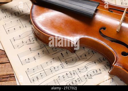 Violin and music sheets on wooden table, closeup Stock Photo