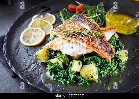 Fish dish - fried sea bass fillet and boiled Swiss chard with potatoes garlic and olive oil.  Mediterranean healthy food with fillet fish Stock Photo