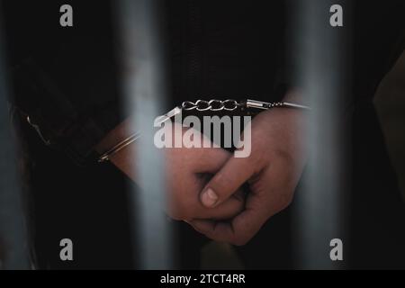 Male hands in handcuffs black background. a handcuffed prisoner in a prison or courtroom. Stock Photo