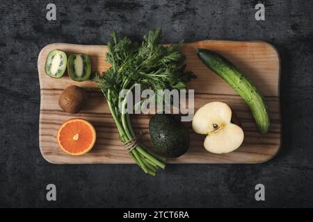 Vegan food ingredients are placed on a cutting board on dark concrete. Stock Photo