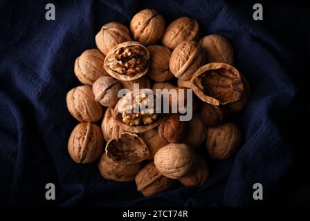 A group of walnuts on a blue old cloth by the window in a dark place (out of focus, macro) Stock Photo