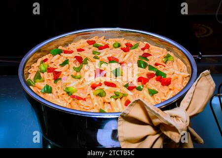 Cooking chicken fajita pasta with bell peppers onions and mushrooms in large stainless steel wok pan Stock Photo