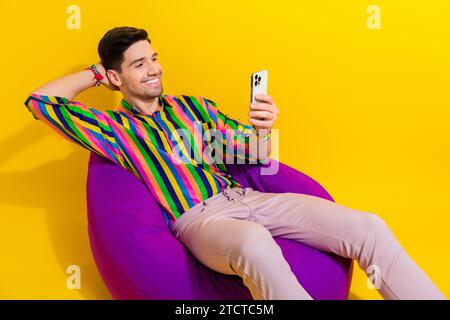 Photo the disco man using smartphone gadget during waiting for his turn in the lounge area surfing news isolated on yellow color background Stock Photo