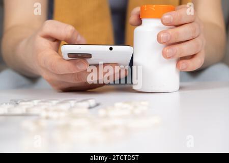 Woman reading instructions for the use of medication on the Internet using a smartphone. Online appointment with a doctor Stock Photo