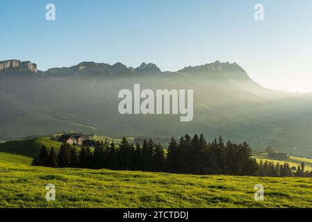 Rural landscape in the Appenzell region with farm houses and meadows in the last light of the evening sun, view to the Alpstein mountains with Saentis Stock Photo