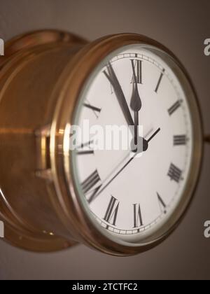 Closeup of an old ship's clock with Roman numerals approaching midnight. Stock Photo