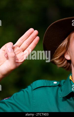 Boy scout in uniform performs three finger salute. Scout symbol hand gesture. France. Stock Photo