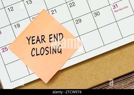 Year end closing text on sticky note and stuck to a calendar background. Stock Photo