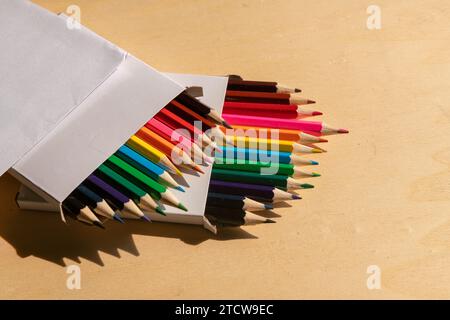 colored pencils: vibrant assortment neatly arranged on a wooden table, ready to unleash creativity with their range of vibrant colours. Stock Photo