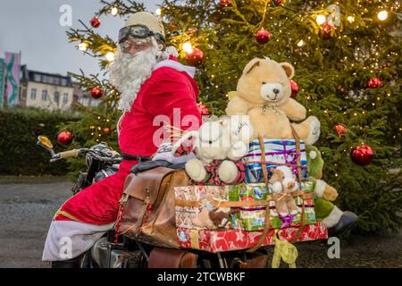 Cottbus, Germany. 14th Dec, 2023. A man dressed as Santa Claus stands in front of an illuminated Christmas tree on his vintage motorcycle. Credit: Frank Hammerschmidt/dpa/Alamy Live News Stock Photo