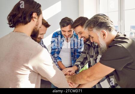 Group of a happy smiling men friends stacking hands in unity. Teamwork Concept. Stock Photo