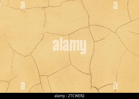 Old stucco plaster surface with cracks, close up grunge texture of yellow painted cement, concrete wall texture background. Wallpaper, backdrop, archi Stock Photo