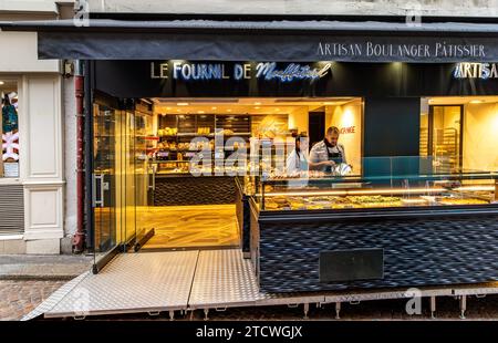 Two people behind the counter at Le Fournil de Mouffetard a Boulangerie Pâtisserie on Rue Mouffetard in the 5th arrondissement of Paris, France Stock Photo