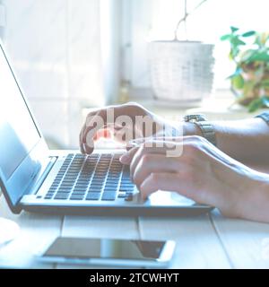 Laptop, phone. Programmer's hands working on laptop keyboard. Stock Photo